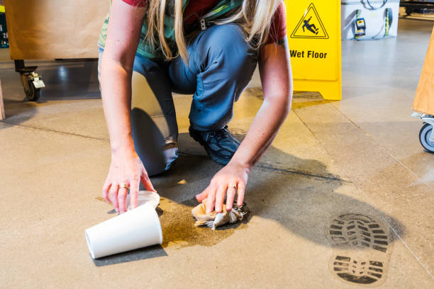 An employee cleaning-up a spilled coffee cup in a retail store. A workplace health and safety topic.