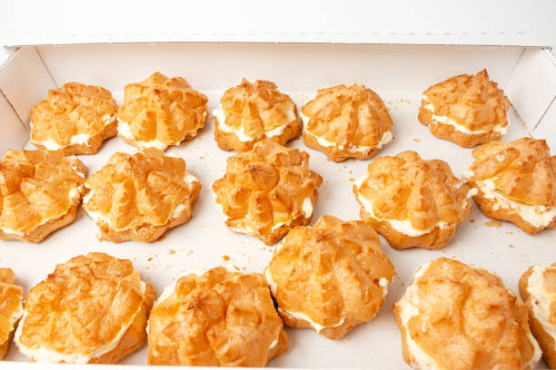 A tray of pastries with a white box underneath. The pastries are small and golden brown Cake with white filling on a white background.