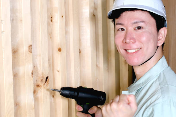 Asian male worker working with an electric drill on site