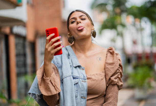 istock young female student using a cell phone and making funny faces at the camera outdoors in the city 2192521886