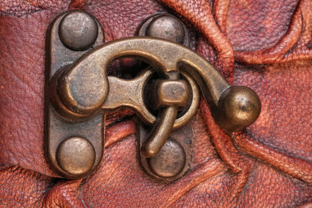 Close-up of an antique brass latch on a textured leather surface.