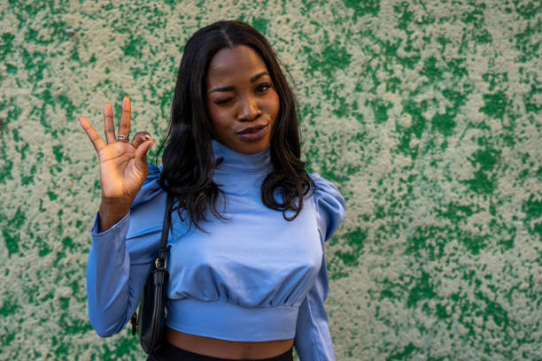 Portrait of a beautiful young black woman winking and gesturing ok sign