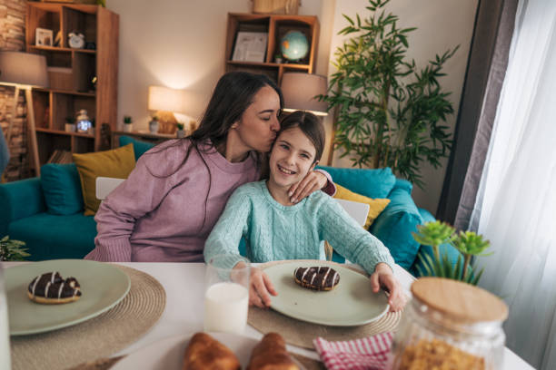istock A mother and daughter sit together at the dining table, sharing a delightful breakfast of chocolate donuts and glasses of milk. 2192524855