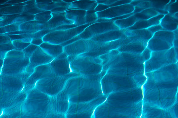 Blue swimming pool water surface and ripple wave background. Summer abstract reflection caustics in swimming pool