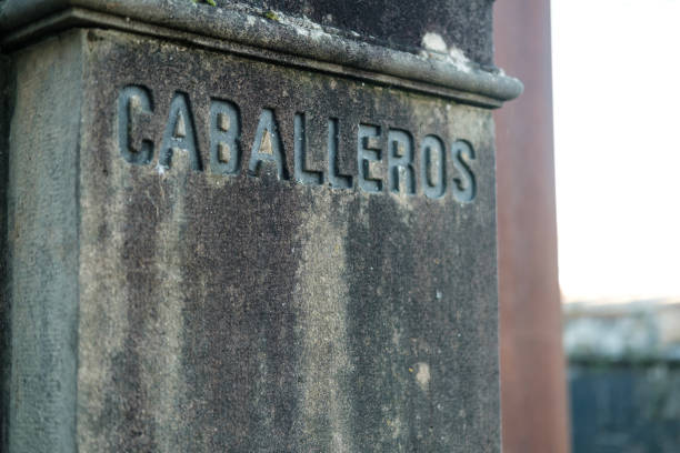Close-up view of a weathered stone pillar featuring the engraved word caballeros, signifying a men's restroom in spanish, adding a touch of traditional charm