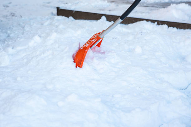 istock Bright Orange Snow Shovel Clearing Thick Snow on Raised Platform 2192535559