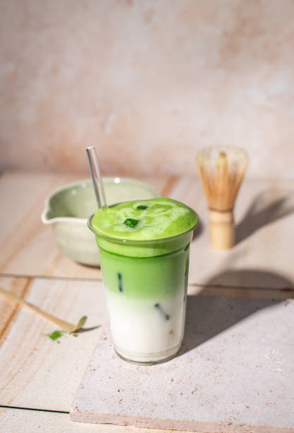 istock Green Tea Iced Matcha Latte prepared fresh on bright kitchen counter with milk, ice cubes and frothy matcha foam 2192535734