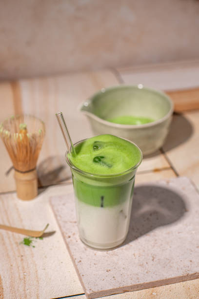 istock Green Tea Iced Matcha Latte prepared fresh on bright kitchen counter with milk, ice cubes and frothy matcha foam 2192535749