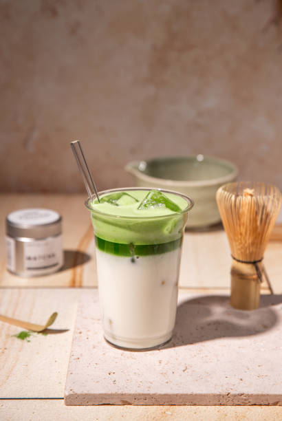 istock Green Tea Iced Matcha Latte prepared fresh on bright kitchen counter with milk, ice cubes and frothy matcha foam 2192535766