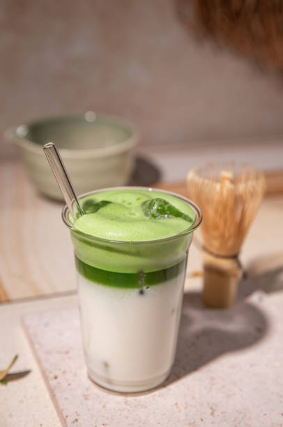 istock Green Tea Iced Matcha Latte prepared fresh on bright kitchen counter with milk, ice cubes and frothy matcha foam 2192535769