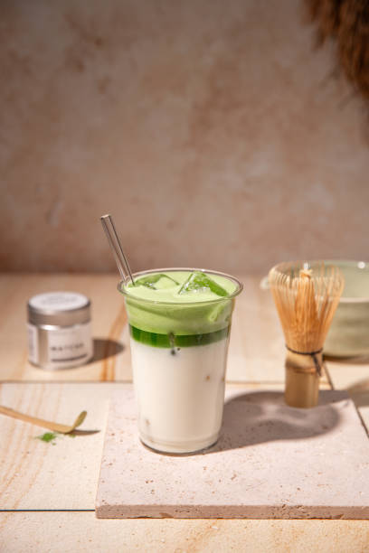 istock Green Tea Iced Matcha Latte prepared fresh on bright kitchen counter with milk, ice cubes and frothy matcha foam 2192535773