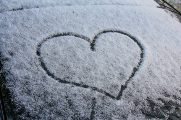 istock Heart shape drawn in snow on a car windshield during winter season 2192539313
