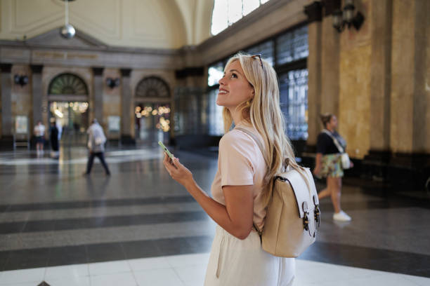 istock Tourist holding smartphone and looking around at train station 2192539395