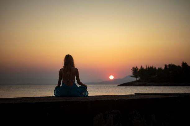 istock Serene woman meditating at sunset 2192541088