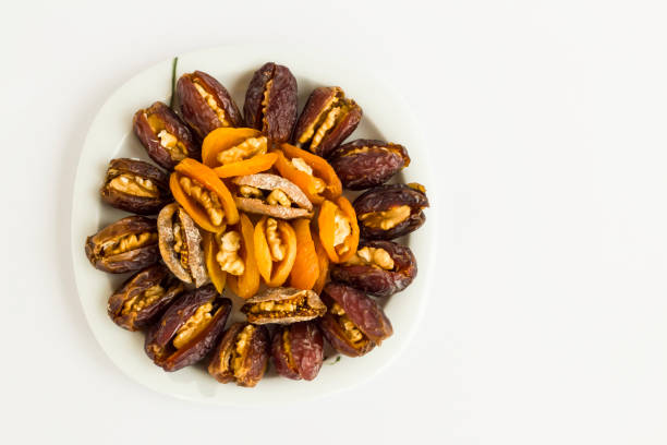 Walnuts are wrapped in dates and dried apricot fruits,designed in plate on white surface with copy space.Ramadan Concept