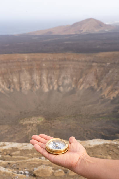 Hand holding a compass while navigating the vast volcanic crater landscape in Lanzarote, located in the stunning Canary Islands