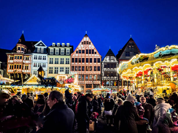 Lovely night at the traditional German Christmas Market in Frankfurt with happy crowds enjoying traditional food and beverages while taking in the shopping and entertainment choices.