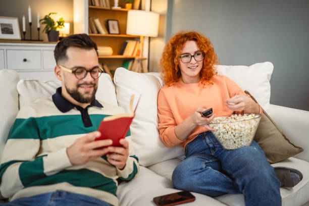 istock cheerful couple enjoy together on sofa with book and popcorn 2192549758
