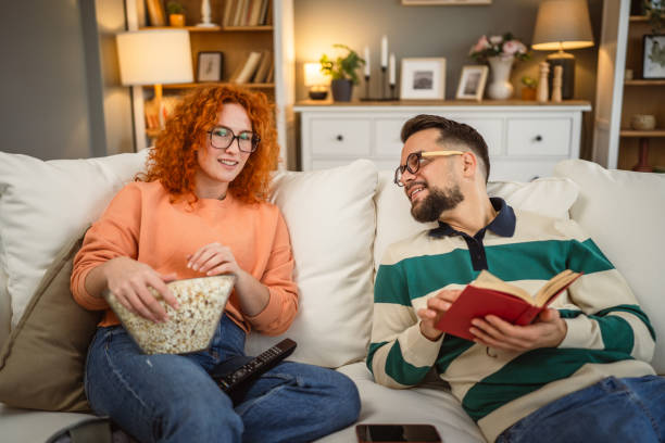istock cheerful couple enjoy together on sofa with book and popcorn 2192549763