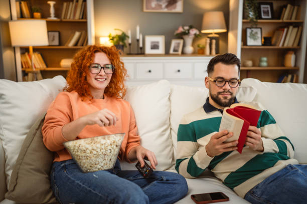 istock cheerful couple enjoy together on sofa with book and popcorn 2192549815