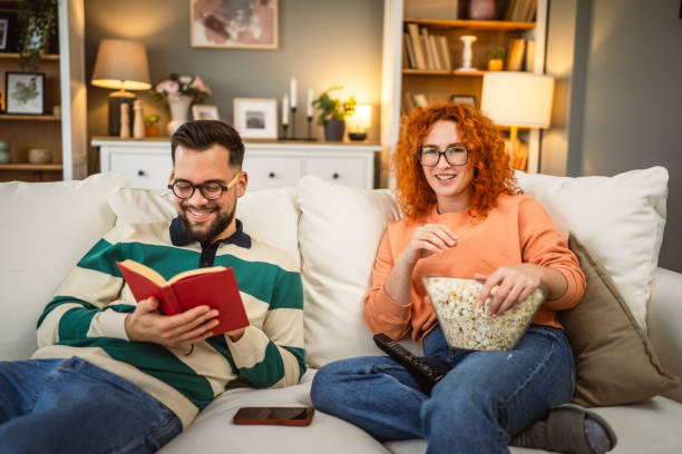 istock cheerful couple enjoy together on sofa with book and popcorn 2192549861