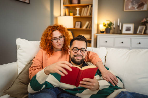 istock cheerful couple enjoy together on sofa and read book together 2192549867