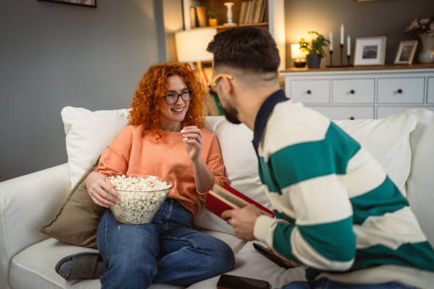 istock cheerful couple enjoy together on sofa with book and popcorn 2192549910