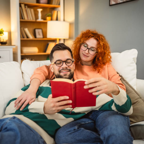 istock cheerful couple enjoy together on sofa and read book together 2192549971