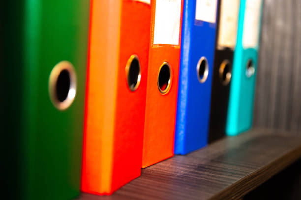 Colorful files on a shelf to assort the documents in the office. Red, orange and green plastic folders.