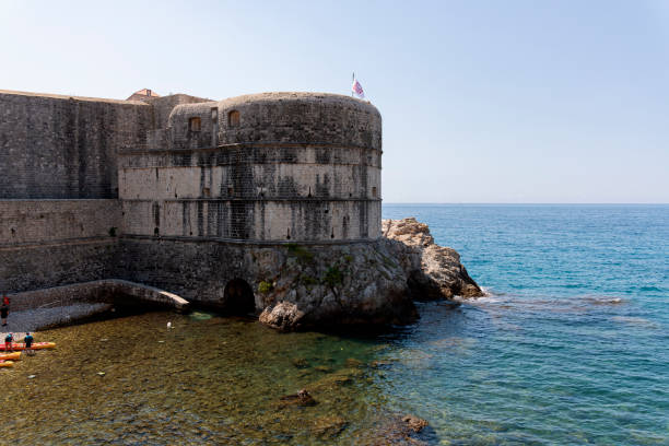A picturesque view of kayakers exploring the crystal-clear waters surrounding Dubrovnik’s iconic ancient walls, offering a unique perspective of this UNESCO World Heritage Site