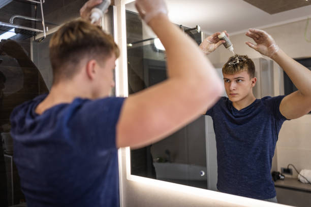 istock Young Man Applying Hair Dye in Modern Bathroom Mirror 2192556007