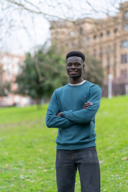 istock Young black man smiling with arms crossed in a park 2192557777