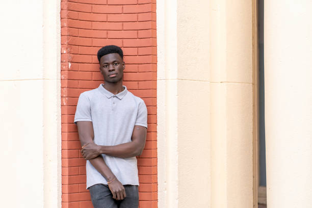 istock Young black man posing leaning against a brick wall 2192557799