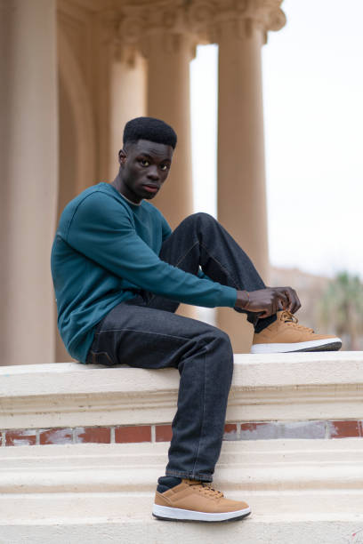 istock Young man tying his shoes while sitting on a low wall 2192557930