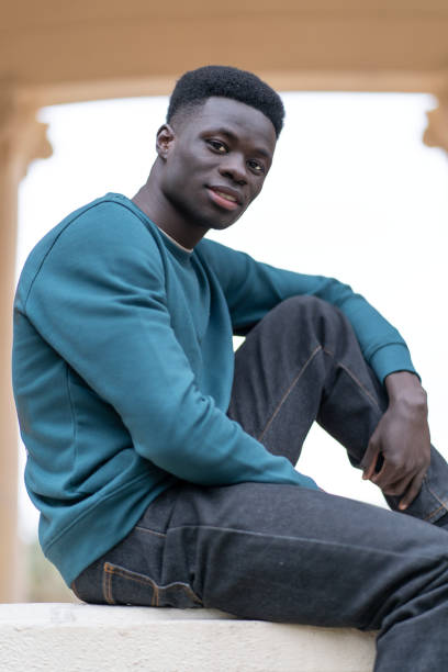 istock Young black man sitting and smiling in an urban setting 2192557959