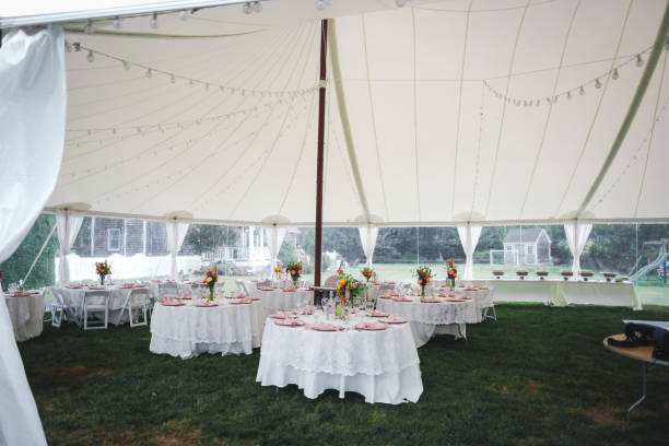 istock Wedding reception tables under tent with white table cloth and floral centerpiece 2192559897