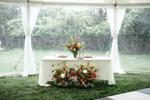 istock Wedding reception tables under tent with white table cloth and floral centerpiece 2192559900