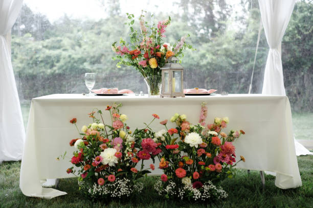 istock Wedding reception tables under tent with white table cloth and floral centerpiece 2192559901
