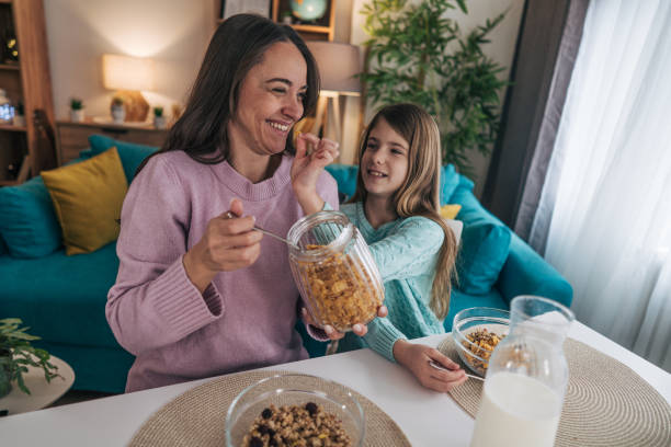 istock The mother is carefully spooning cornflakes into a bowl, preparing breakfast for herself and her daughter. Her movements are gentle and measured 2192563475
