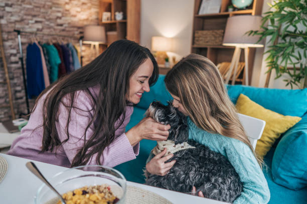 istock Mother and daughter sit together at the dining table, enjoying breakfast. At the same time, both love for their dog 2192564300