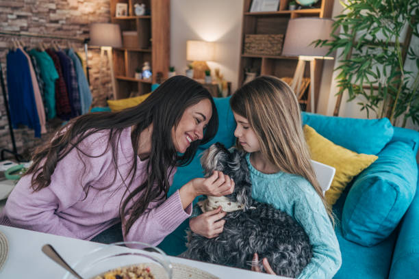 istock Mother and daughter sit together at the dining table, enjoying breakfast. At the same time, both love for their dog 2192564483