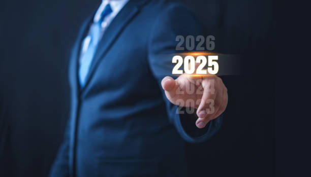 istock Business man in suit touch or select hand pointing on year 2025 text with virtual screen on black background 2192574779