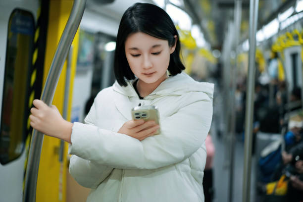istock Young Woman Utilizing Smartphone in a Modern Subway Train 2192585175