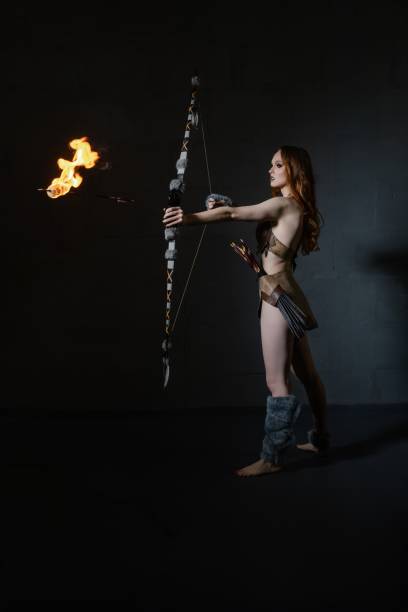 A skilled archer draws back a flaming arrow, showcasing her talent in a dramatic dark environment.