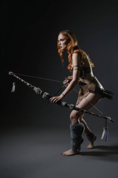 istock Woman dressed in survival attire poses with a bow in a studio setting 2192589480
