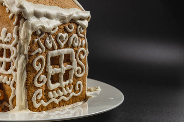 Homemade gingerbread house on a plate on a black background High quality photo.