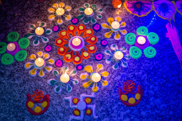 A close-up shot of a woman's hand adorned with bangles delicately decorating a surface with vibrant flower petals and small oil lamps (diyas). The colorful petals and warm glow of diyas create an intricate pattern adds a touch of elegance and festivity. This image captures the essence of tradition and celebration, showcasing the intricate details involved in preparing for a special occasion of Diwali. The woman's gentle touch reflects care and artistry in creating a beautiful atmosphere