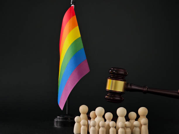 istock Rainbow flag stands proudly next to gavel and wooden figures representing unity and justice for the LGBTQ+ community 2192599002