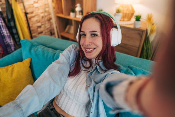 istock Woman sitting on a turquoise couch, taking a selfie. 2192609595