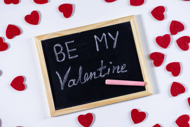 istock chalkboard with be my valentine written in white chalk surrounded by scattered red felt hearts on a white background symbolizing love and romance 2192610733